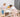 Alt text: Two young children standing on wooden Montessori learning towers while baking together at a kitchen table.
