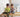 Two young children playing together on a wooden Montessori rocker in a cosy, light-filled kids’ room with natural furniture and a soft, calm atmosphere.
